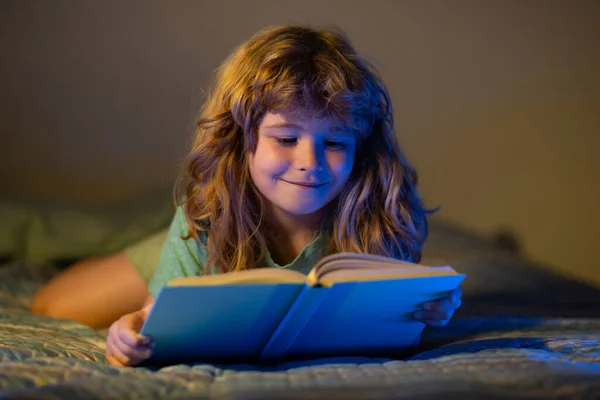 子供は本を読む。寝る前にベッドで本を読んでいる子供。子供は就寝時に本を読んでいます。少年読書就寝時の話おとぎ話. — ストック写真