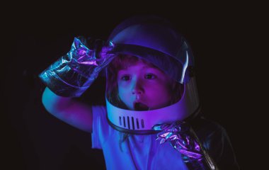 Küçük bir çocuk astronot olup uzaya uçmayı hayal ediyor. Uzay giysisi ve kask rüyasındaki çocuklar. Heyecanlı çocukların yüzlerini neon rengine yakın tut.
