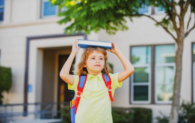 İlkokuldan bir çocuk. Gözlüklü mutlu çocuk ilk kez okula gidiyor. Okul çantası ve kitabı olan bir çocuk. Okula geri dön..