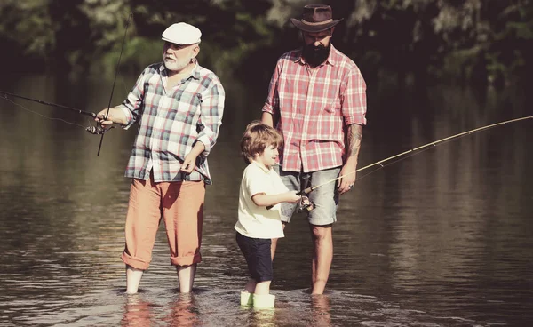 Grandfather with son and grandson having fun in river. Father, son and grandfather on fishing trip. Men hobby.