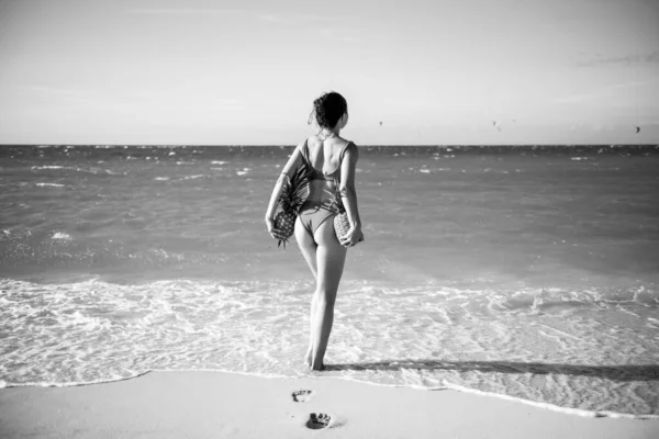 Frau im Badeanzug mit muskulösem Gesäß hält Ananas in der Nähe des Sandstrandes der Insel. Sommer sexy Früchte. Heiße Sommerzeit glücklicher junger Frauen mit Ananas. Sexy Models im Tropenurlaub. — Stockfoto