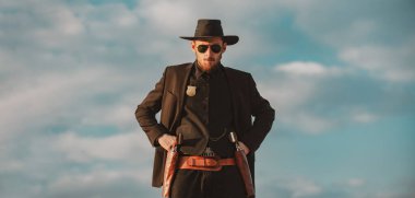 Siyah takım elbiseli ve kovboy şapkalı şerif, afiş. Vahşi batı, batı, klasik tabanca tabancası ve mühimmatı olan adam..