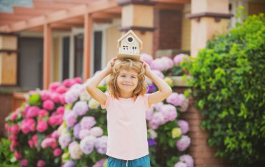 Oyuncak evle oynayan komik çocuk. Küçük oyuncak ahşap evi olan çocuk, yeni ev kavramı.