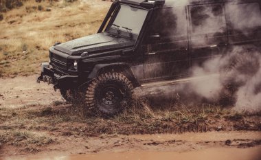 Dağ yolundaki köylere yapılan off-road cipi seferi. Çamurlu yolda su sıçratan klasik 4x4 araba. Off road vagonu.