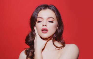 Kırmızıda güzel bir kadın modelin güzel portresi. Şehvetli, taze tenli, parlak saçlı, yüzü kapalı, çıplak makyajlı güzel bir kadın..