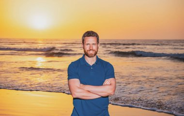 Yakışıklı, gülümseyen adam sahilde yaz gününün tadını çıkarıyor..