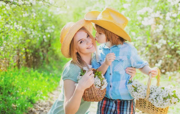 Happy mother family with son at picnic basket with blossom bloom flowers. Family mom with kid sitting on the grass in park. — Stock Photo, Image