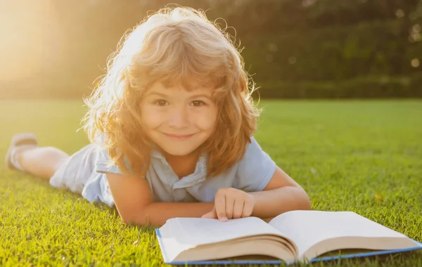 Kleine jongen leest een boek in de zomer zonsondergang licht. — Stockfoto