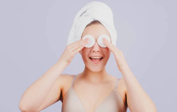 Funny beautiful girl with clean fresh skin. Facial treatment. Cosmetology beauty and spa. Girl apply skincare cream on face, woman wrap towel on head put facial creme on doing morning healthy skin. — Stock Photo, Image