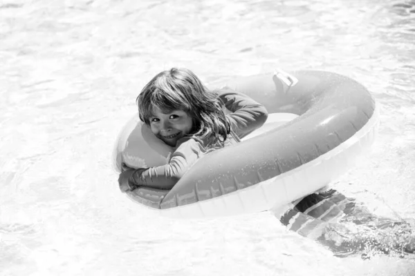 Niño en la piscina de verano. Vacaciones de verano para niños. Fin de semana infantil de verano. Un chico en la piscina. Niño en aquapark en círculo de goma inflable. —  Fotos de Stock