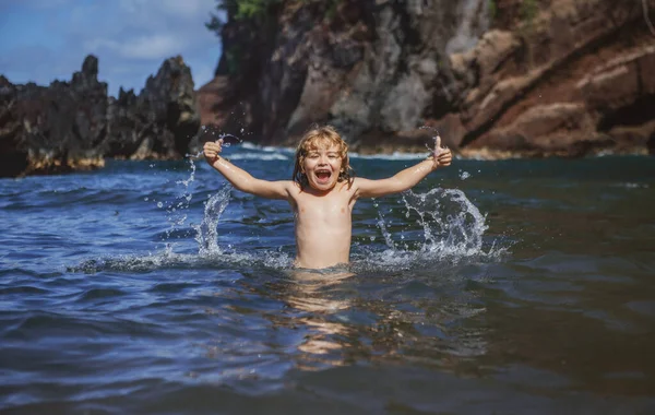 Enfant jouant dans l'eau de mer. Il saute dans les vagues de la mer. Vacances d'enfants sur la plage. Petit garçon excité nageant pendant les vacances d'été. — Photo