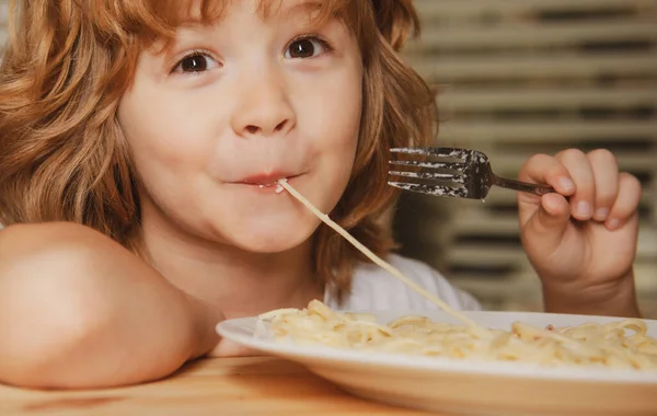 Portret uroczego chłopca jedzącego makaron, spaghetti. Zamknij buzię białym dzieciakom. Zbliżenie głowa zabawny dzieciak. — Zdjęcie stockowe