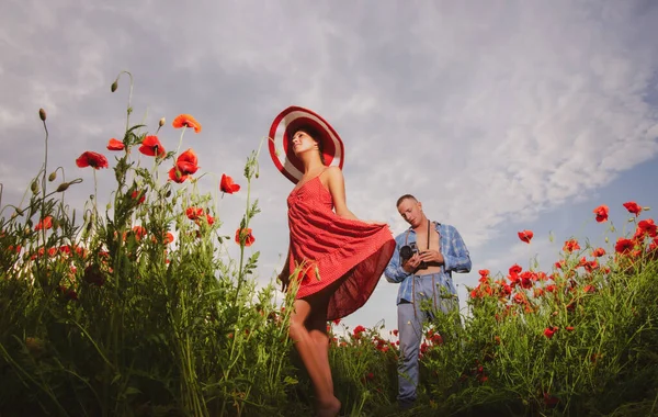 Фотограф, стреляющий в женщину в платье на маковом летнем поле. Благополучие влюбленной семьи, влюбленная пара на даче. — стоковое фото