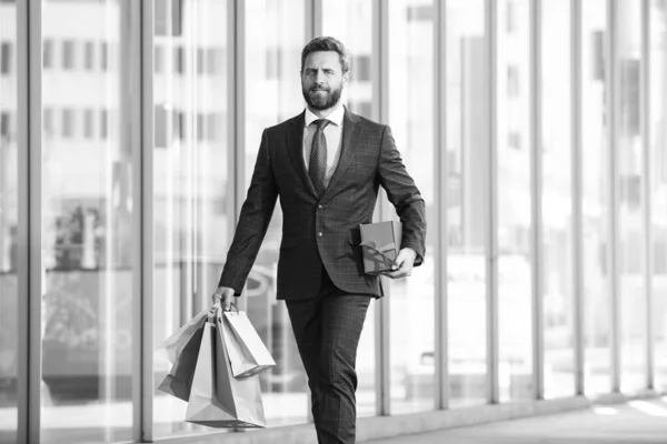 Uomo d'affari che tiene le borse della spesa e cammina in negozio. Shopping e pagamento. Shopaholic concetto di shopping. — Foto Stock