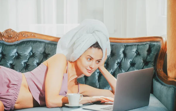 Distanza di lavoro online dal letto. Giovane donna attraente con caffè e laptop rilassante a casa. Accogliente pigro mattinata. Bella ragazza online chatta al mattino sul letto. — Foto Stock