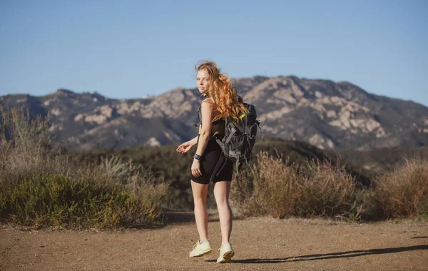 Koncept Backpacking cestovního ruchu. Žena turistka s batohem vyšplhala na kopec a při pohledu na ohromující a divoké krajiny. — Stock fotografie