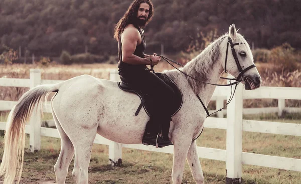 Homem sexy a cavalo. Jovem jóquei treinando seu cavalo para um passeio. Boa aparência, cowboy hunky monta cavalo na bela natureza do lado do país . — Fotografia de Stock