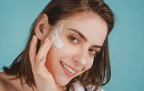Beautiful young woman with clean fresh skin applying moisturizer cream on her pretty face. — Stock Photo, Image