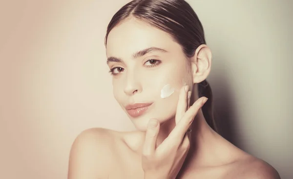 Beautiful woman spreading cream on her face. Skin cream concept. Facial care for female. Keep skin hydrated regularly moisturizing cream. Fresh healthy skin concept. Taking good care of her skin — Stock Photo, Image
