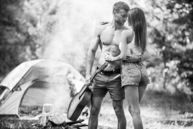 Kamp çadırının yanında genç ve seksi bir çift. Birbirine aşık kamp çifti. Sevgili turistler doğada rahatlar. Aşıklarla kamp gezisi. Kamp ateşi yanında tasasız bir çift, özgürlük kavramı..