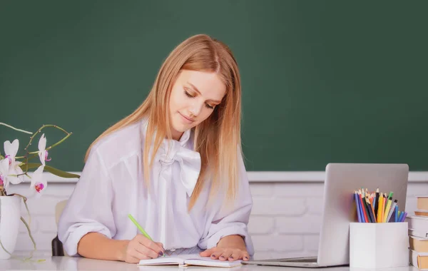 Porträt einer Studentin, die in der Schule oder an der Universität auf einem Notizbuch schreibt. — Stockfoto