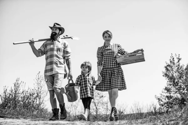 春に果樹園で父と母を持つ小さな男の子。農地で笑顔の家族。農業分野を歩く家族. — ストック写真