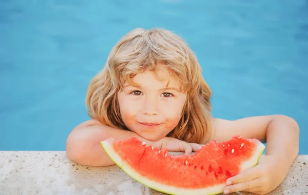 Un niño gracioso juega en la piscina. El niño come una sandía dulce, disfrutar del verano. Niñez despreocupada. — Foto de Stock