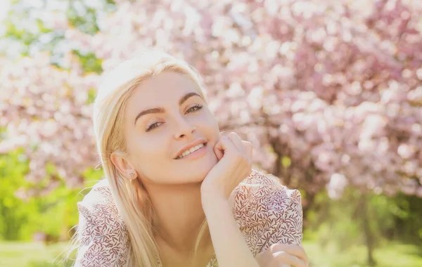 Gelukkig meisje met bloemen in het gras. Schattig gezicht van lachende jonge vrouw in het voorjaar. Droomvrouw. — Stockfoto