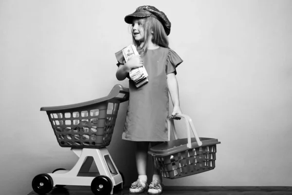 ショッピングカートの女の子。青で隔離された幸せな子供のショッピング。お金で少しお店の笑顔。子供の買い物ファッション。買い物と販売。ブラック・フライデー. — ストック写真