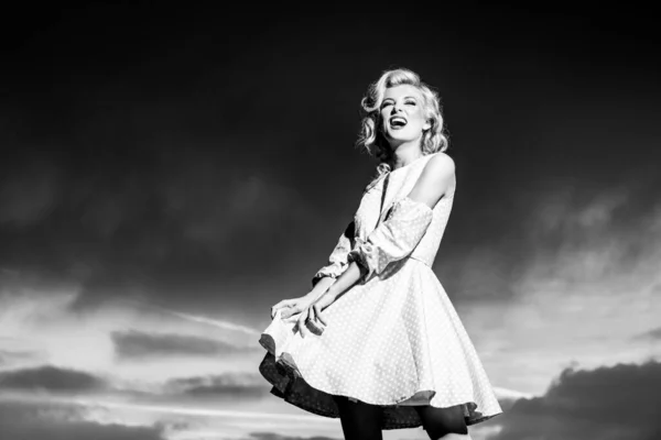 Vrouw in Monroe jurk aan dramatische hemel. Stijlvolle mode vrouw poseren buiten. Aantrekkelijke jonge vrouw in sexy jurk genieten zomer. — Stockfoto