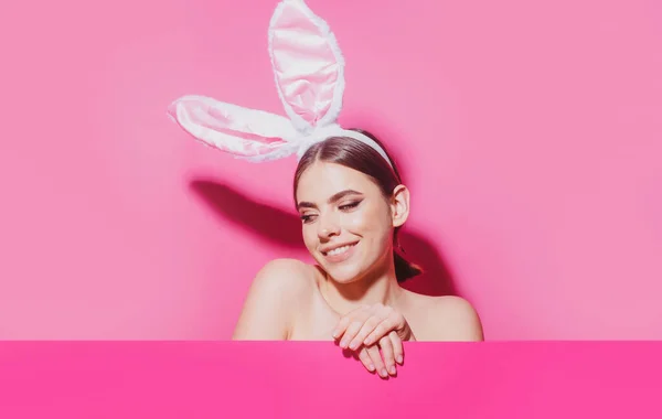 Mulher da Páscoa com orelhas de coelho. Menina bonita com orelhas de coelho e cartaz em branco rosa. — Fotografia de Stock