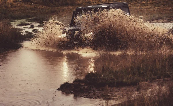 Wasser plätschert im Offroad-Rennen. Geländewagen rasen auf Schmutz. Rad aus nächster Nähe in einer Landschaft mit schlammiger Straße. — Stockfoto