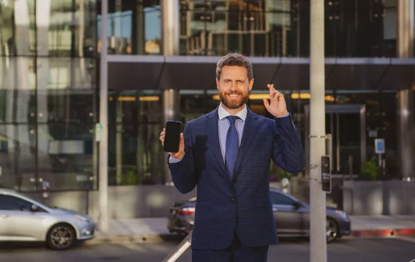 Geschäftsmann mit Telefon. Porträt eines gut gelaunten Büroangestellten, der in der Nähe moderner Büros mit dem Handy telefoniert. — Stockfoto