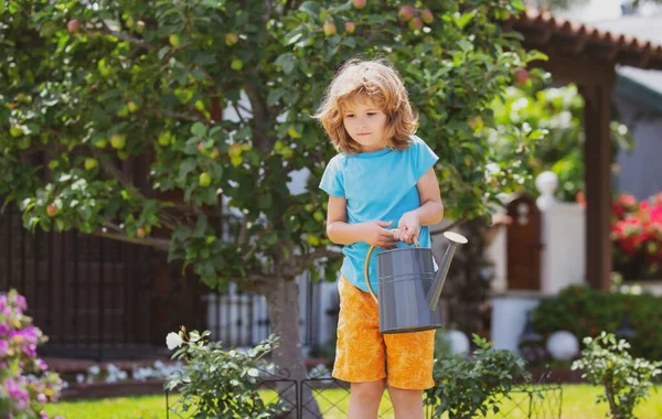 Barn i blomsterträdgård. Porträtt av ett barn som arbetar i trädgården. — Stockfoto