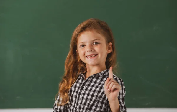 Πορτρέτο της μαθήτριας nerd σχολείο κορίτσι με εκπληκτική έκφραση δείχνοντας με το δάχτυλο εναντίον μαυροπίνακα. Επιστροφή στο σχολείο, πρώτη μέρα στο σχολείο. — Φωτογραφία Αρχείου