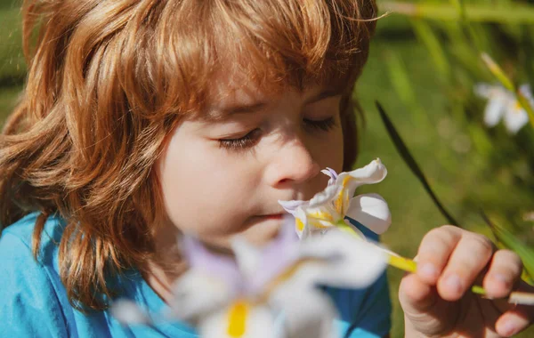 Bonne enfance. Le gamin renifle les fleurs. Concept sans allergie. Enfant mignon dans le parc de fleurs. — Photo
