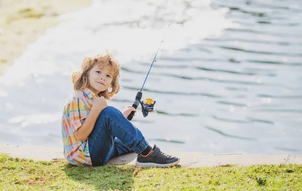 Passatempi per bambini. Sorridente bambino pesca sul lago. Ragazzo con la trottola al fiume. Ritratto di ragazzo eccitato pesca. Ragazzo al molo con asta. — Foto Stock