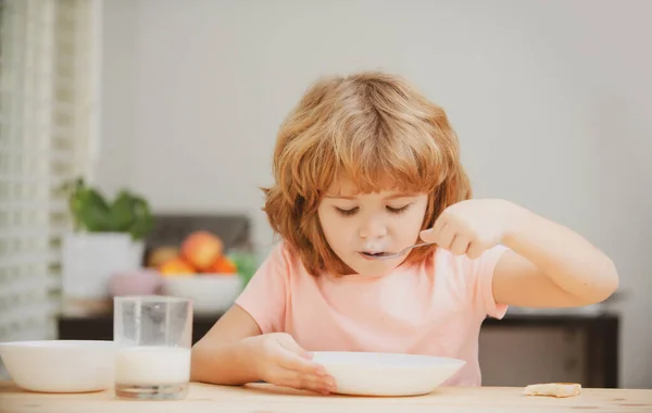 Портрет ребенка, поедающего суп или завтрак, обедающего дома за столом с ложкой. Здоровое питание. — стоковое фото