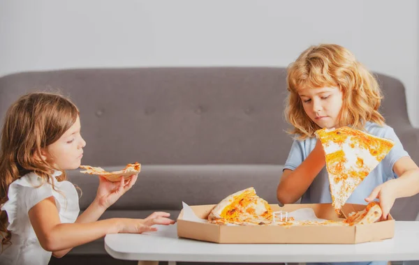 Pizza y niños, rebanadas de pizza en la mano de los niños. Niños comiendo sabrosa pizza de comida rápida con queso. Niños pequeños amigos, chico y chica muerden pizza. — Foto de Stock