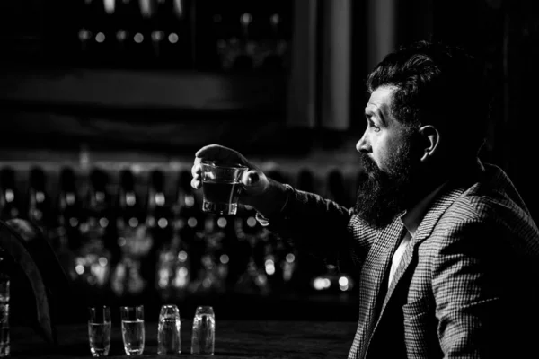 Um cavalheiro barbudo bebe conhaque. A beber o melhor uísque. Homem rico elegante segurando um copo de uísque velho. — Fotografia de Stock