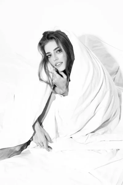 Mujer sensual envuelta en una suave manta sentada en la cama. Mujer sexy sentada en la cama y sonriendo en casa. Dulces sueños. —  Fotos de Stock