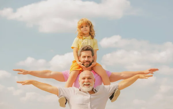 Grand-père avec son fils et son petit-fils levant la main ou volant les bras ouverts. Famille multi-générations. Fête des pères. — Photo