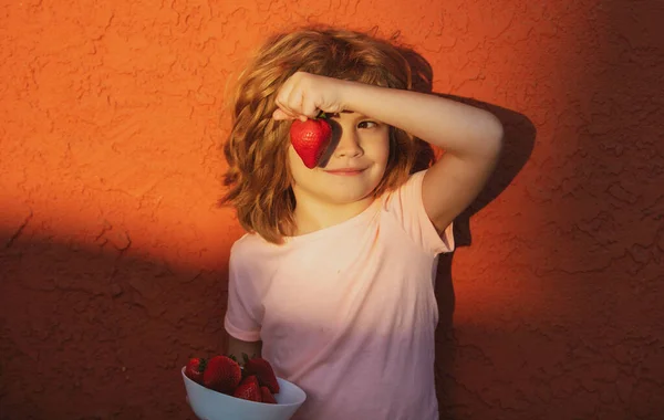 Lustiges Gesicht des süßen kleinen Jungen isst Erdbeeren. — Stockfoto