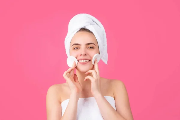 Menina sorridente bonita com pele fresca limpa. Tratamento facial. Cosmetologia beleza e spa. Creme no rosto, mulher envolva toalha na cabeça colocar creme facial na pele saudável. — Fotografia de Stock