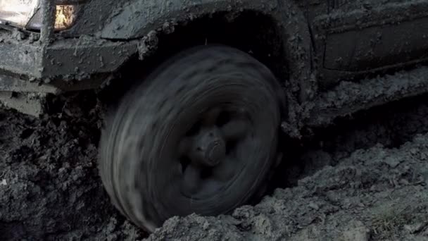 土の遅い動きでホイールの閉鎖ショット。泥だらけの道路と田舎の風景の中にホイールタイヤを閉じ、泥の中に汚れたタイヤ。泥の上のほこりに入る車輪のタイヤとオフロードを動かす. — ストック動画