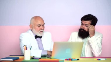 Olgun oğul, büyükbabayı ofisteki dizüstü bilgisayarla açıklıyor. Yaşlı nesil. Adam yaşlı babaya interneti bilgisayarla öğretiyor..