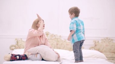 Sevgi dolu aile. Anne yatak odasında çocukla oynuyor. Anne ve oğul evdeki yatakta birlikte oynuyorlar. Annelik ve ebeveynlik, mutlu çocukluk..