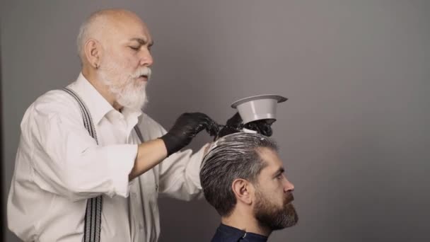 Haarfärbung bei Männern. Gefärbte Haare für einen bärtigen Hipster-Typ. Friseur trägt Färbemittel auf Männerhaare auf. — Stockvideo