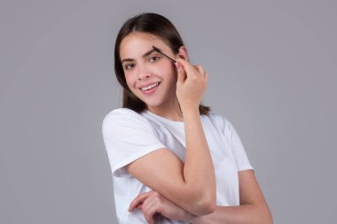 Güzellik salonunda fırçayla kaşlarını tarıyor. Uzun kirpikli ve kalın kaşlı bir kadın. Kaşlar, renkler ve kaplamalar için profesyonel bakım.