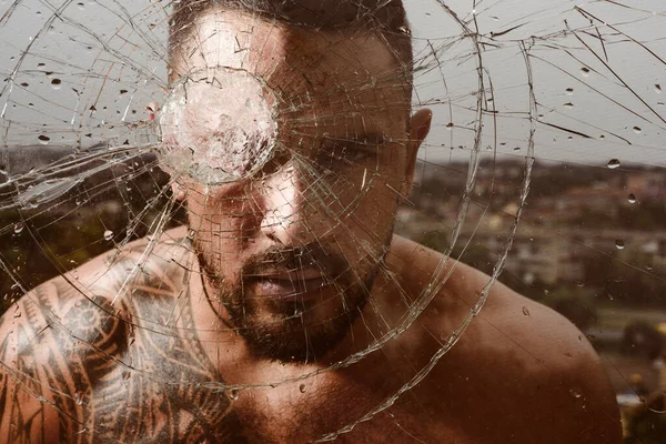 Brutal man, serious face of handsome male model, concept of men power and strong. Gangster man. Dangerous criminal, hooligan guy on cracked bullet glass. — Stock Photo, Image
